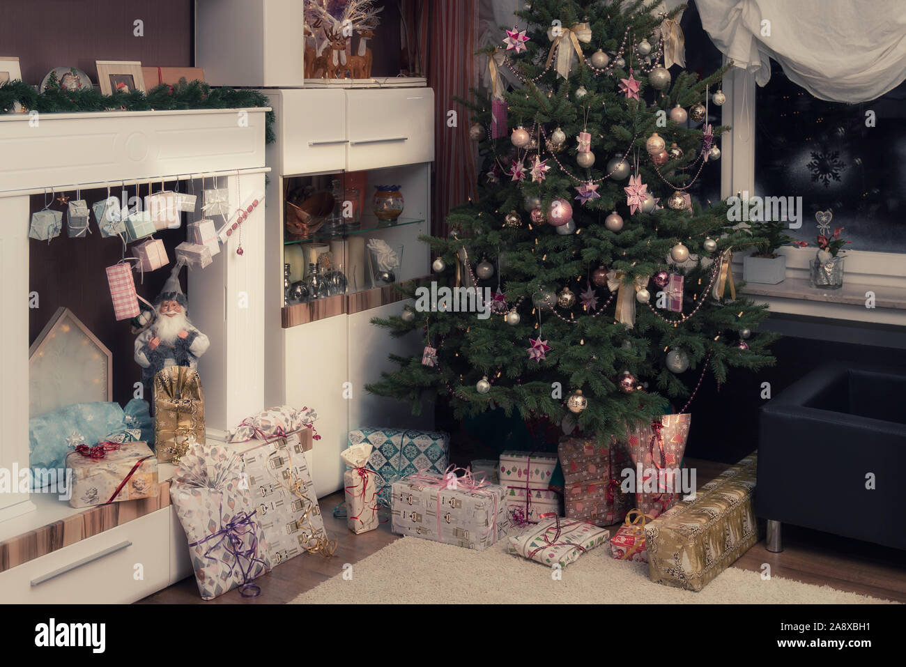 È Notte Santa, l'albero di Natale decorato è nel soggiorno e qui di seguito sono avvolti i regali di Natale. Immagine autentica di una festa privata. Foto Stock