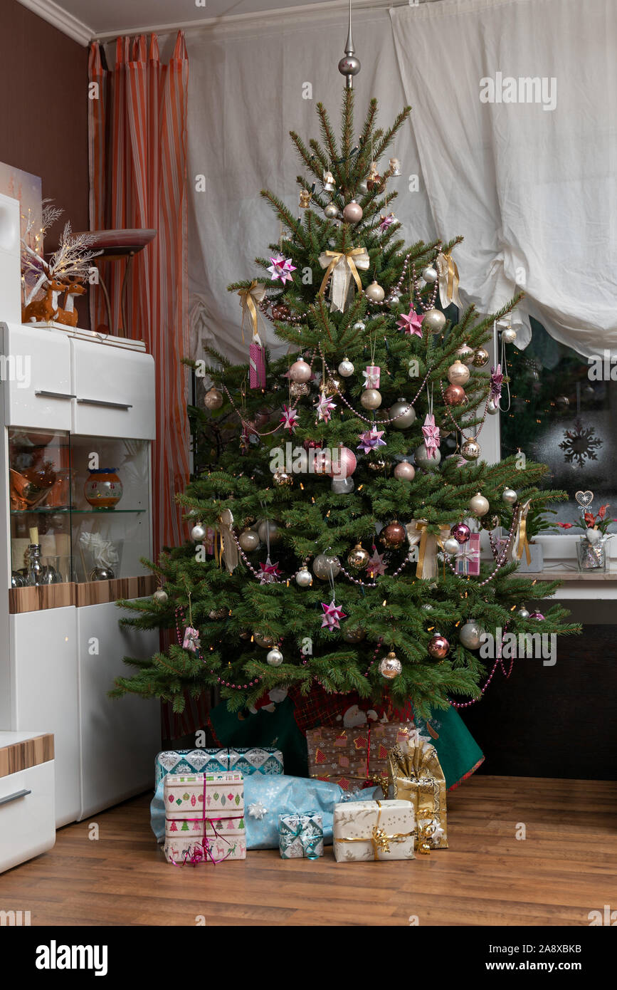 È Notte Santa, l'albero di Natale decorato è nel soggiorno e qui di seguito sono avvolti i regali di Natale. Immagine autentica di una festa privata. Foto Stock