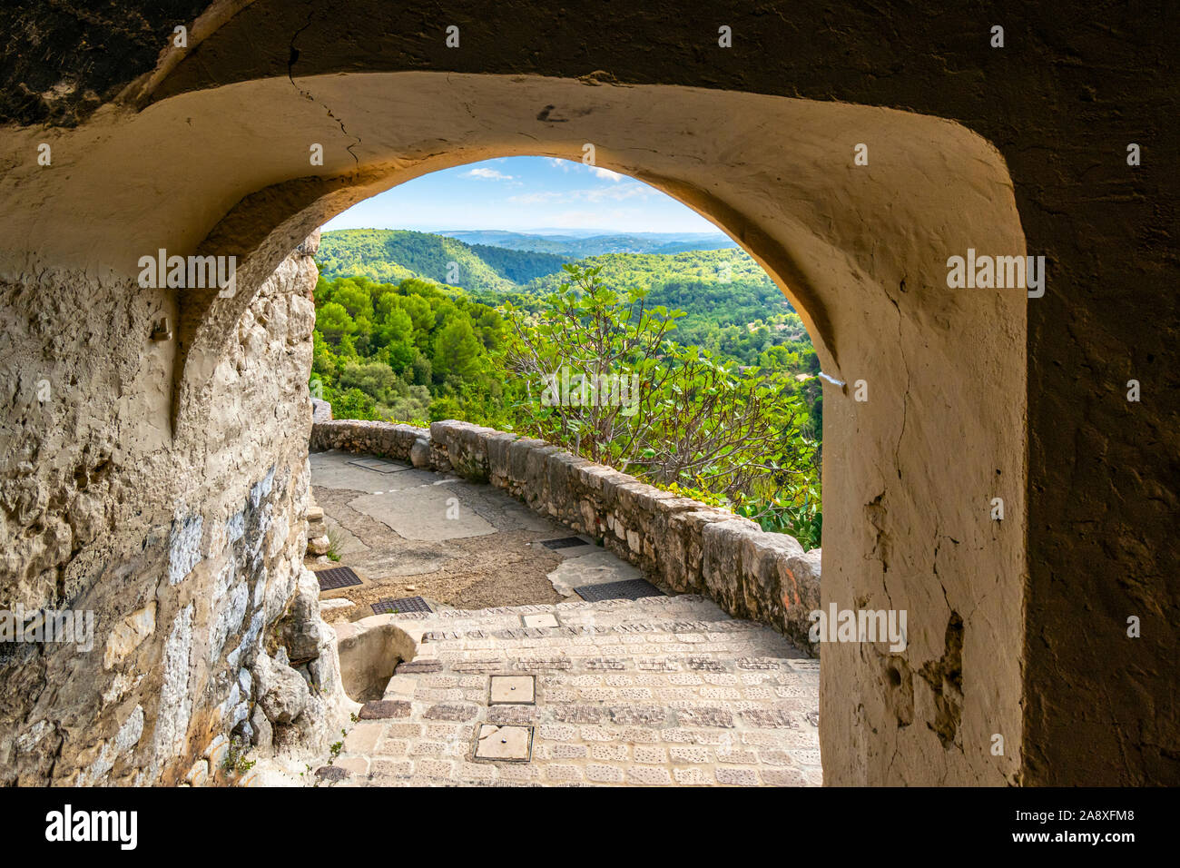 Vista attraverso una pietra portale ad arco dalla medievale hilltop village di Tourrettes sur Loup Francia delle Alpi Marittime montagne del sud della Franc Foto Stock