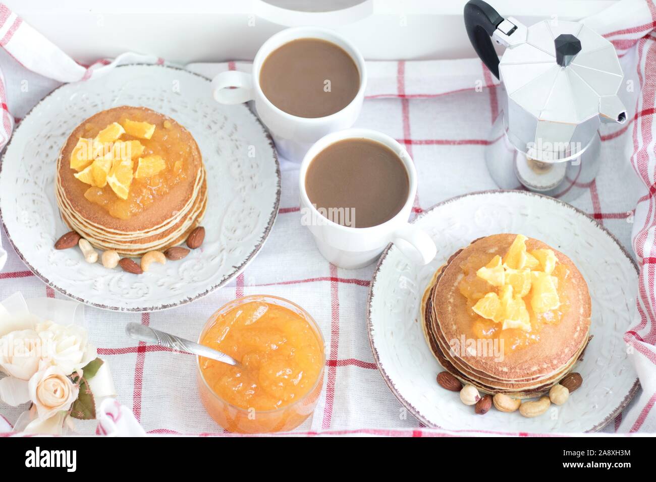 La prima colazione per due persone. American pancake con marmellata di arancia e i dadi sulle piastre di vintage e bianco 2 tazze di caffè. Vista superiore Foto Stock