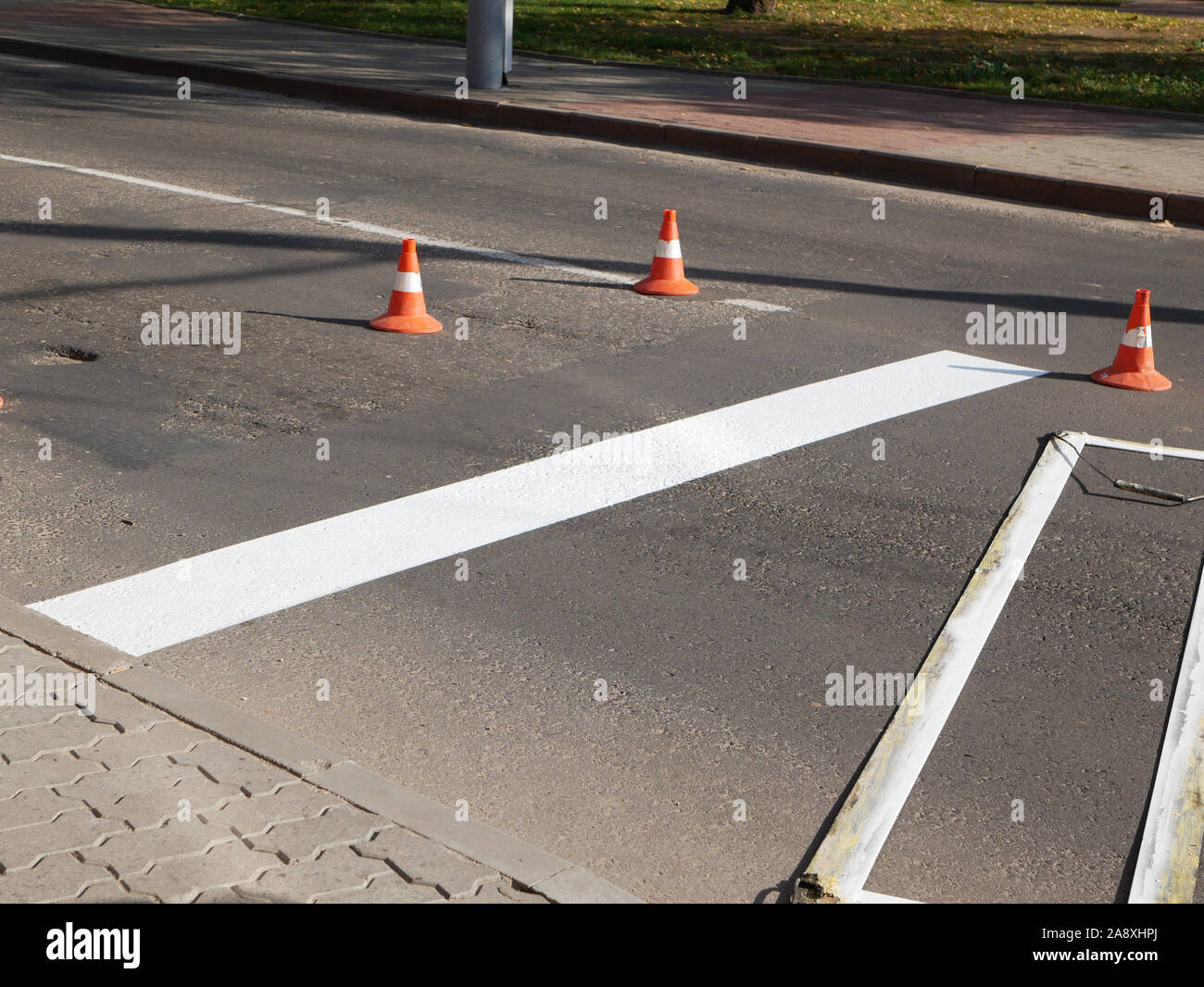 La segnaletica stradale. Disegno di una marcatura su strada. spruzzatura nella costruzione di strada. Lavoratore disegna una linea bianca sulla superficie della strada. Foto Stock