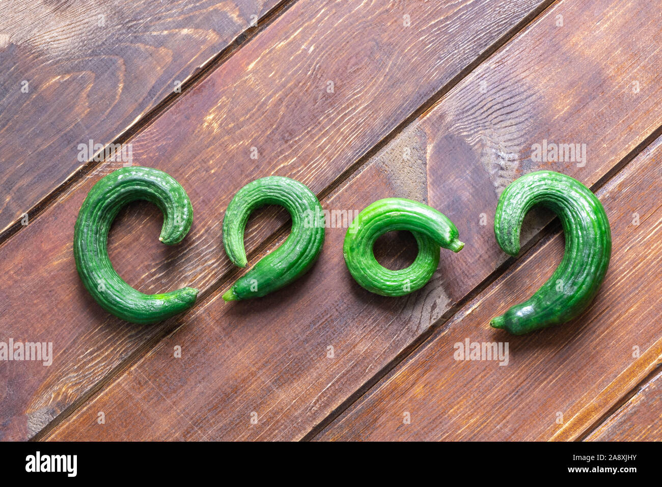 Brutto orto biologico cetrioli su sfondo di legno Foto Stock