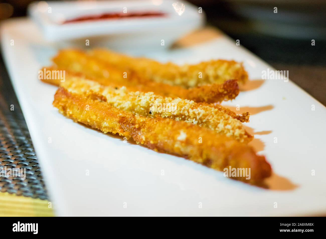 Lunga pepite di pollo strisce con ketchup su un bianco piastra rettangolare Foto Stock