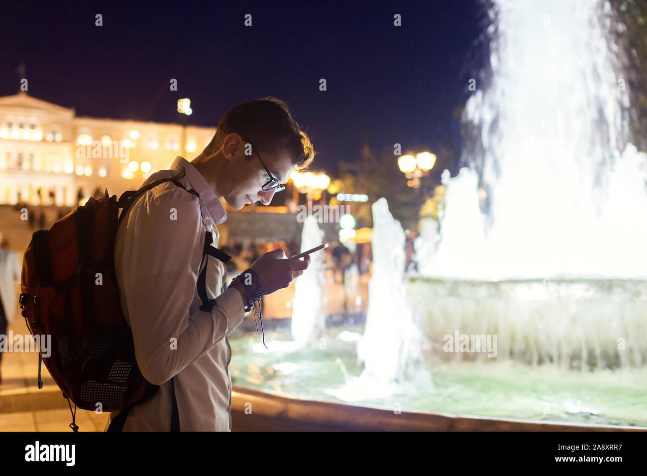 L'uomo tourist usando il navigatore sullo smartphone in Atene, Grecia di notte. Traveler andando visite turistiche Foto Stock