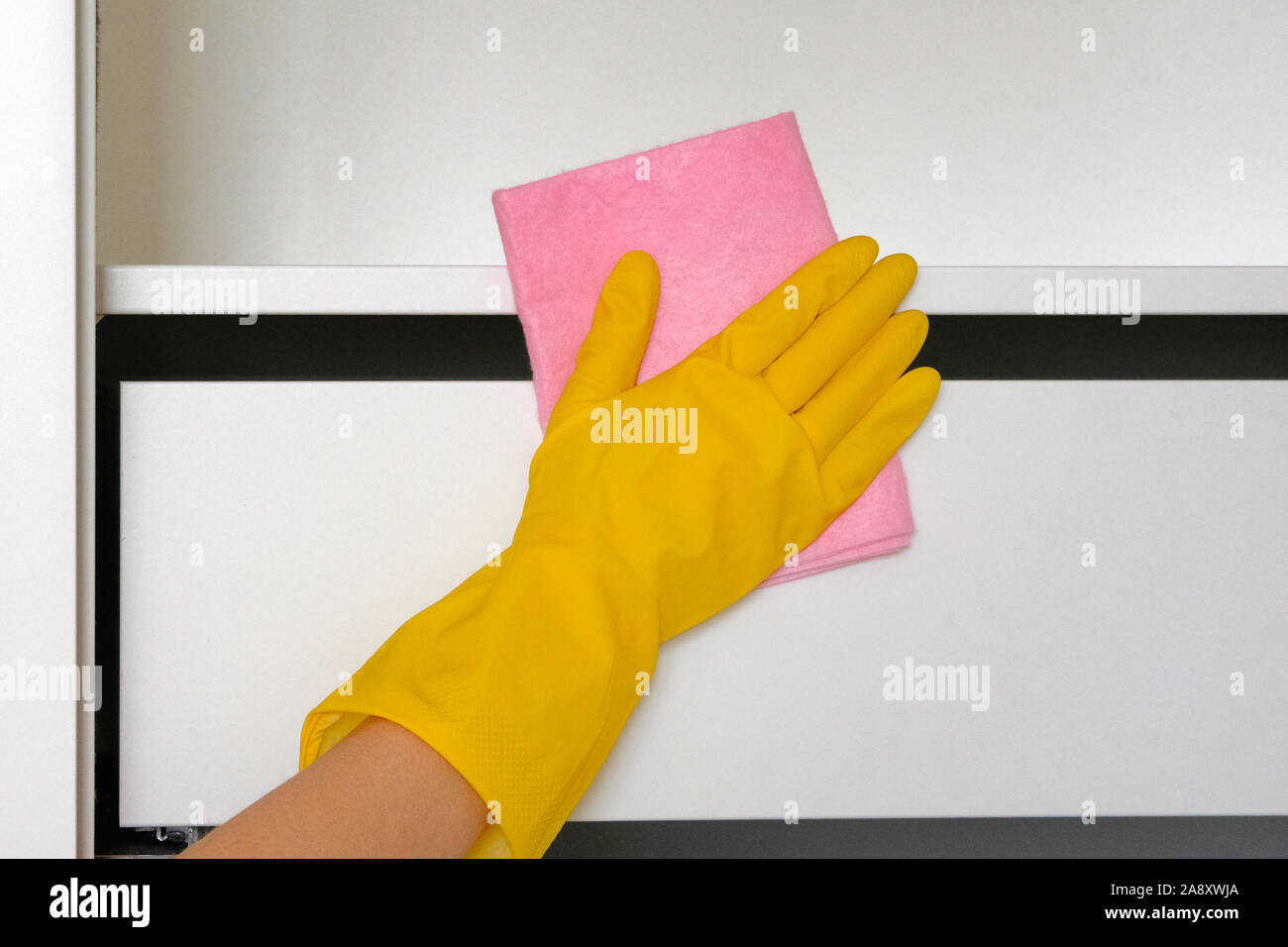 Сleaning o pulire regolarmente. Faccende di casa. Tergivetri ripiano bianco dalla polvere. Salviette casalinga di superficie con panno di colore rosa. Foto Stock