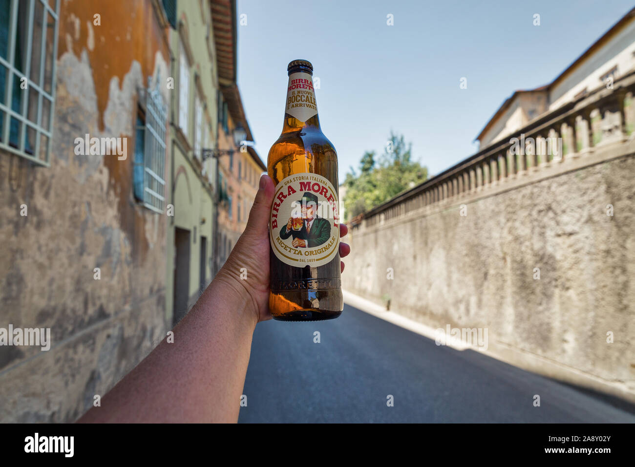 MONTOPOLI, Italia - Luglio 24, 2019: bianco uomo mano trattiene un Moretti birra italiana, antica strada in background. Montopoli in Val d'Arno è un municipali Foto Stock