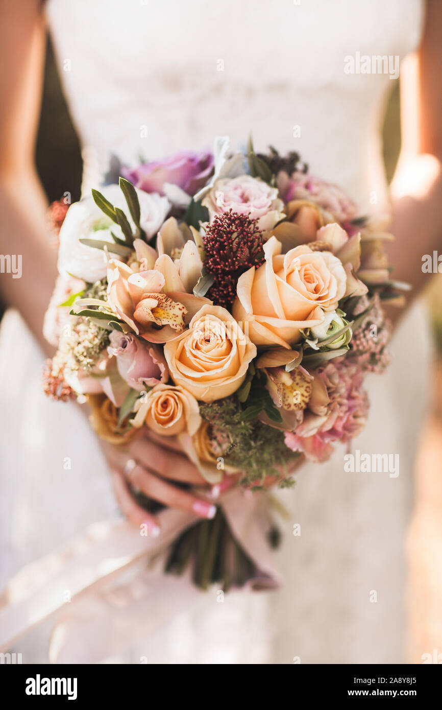 Sposa tenendo nelle mani di piccoli Bouquet nozze in arancione i colori autunnali. Rosa e rose arancione, bianco peonia, fiori secchi e foglie. Foto Stock