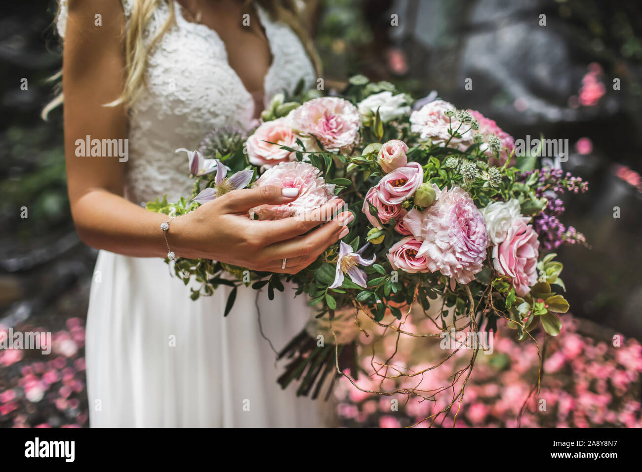 Donna che mantiene in mani grandi bouquet di nozze in stile rustico. Verdi, rosa e rose bianche, coral crisantemo, peonia. Color pastello. Foto Stock