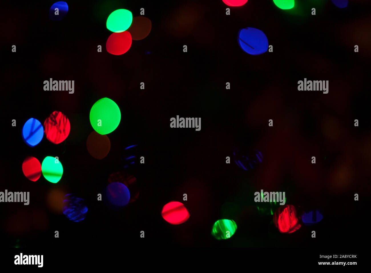 Defocalizzata colorate luci di Natale su albero di Natale sfondo scuro Foto Stock