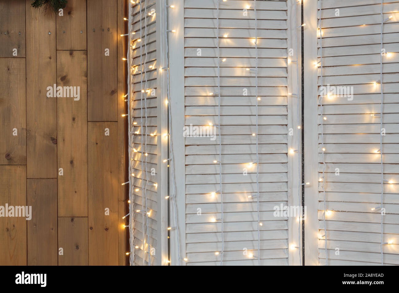 Le luci di Natale la masterizzazione su un bianco sullo sfondo di legno. Sfondo di natale. Foto Stock