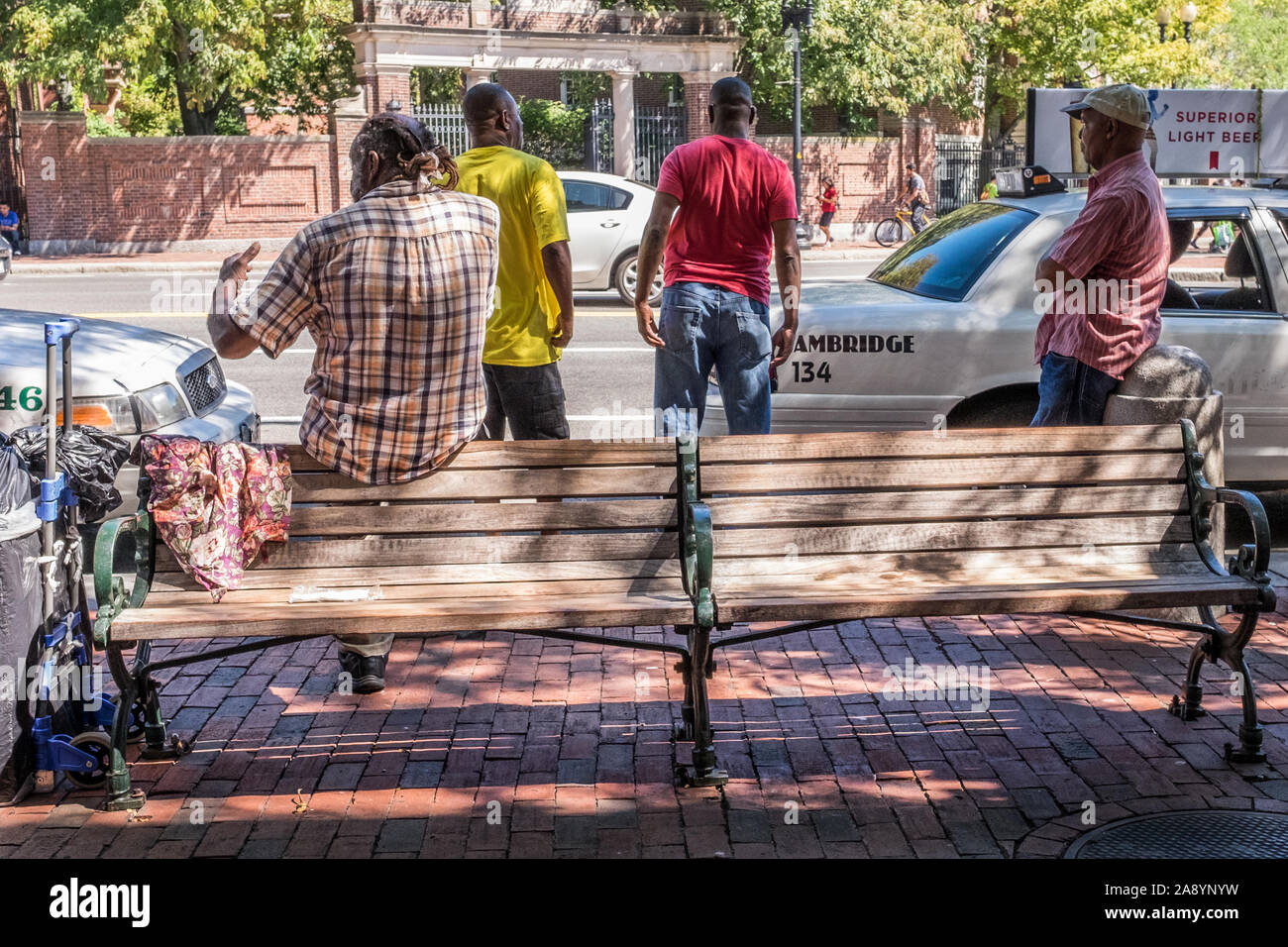 Quattro uomini appendere fuori sulla strada a Harvard Square vicino a un taxi Foto Stock