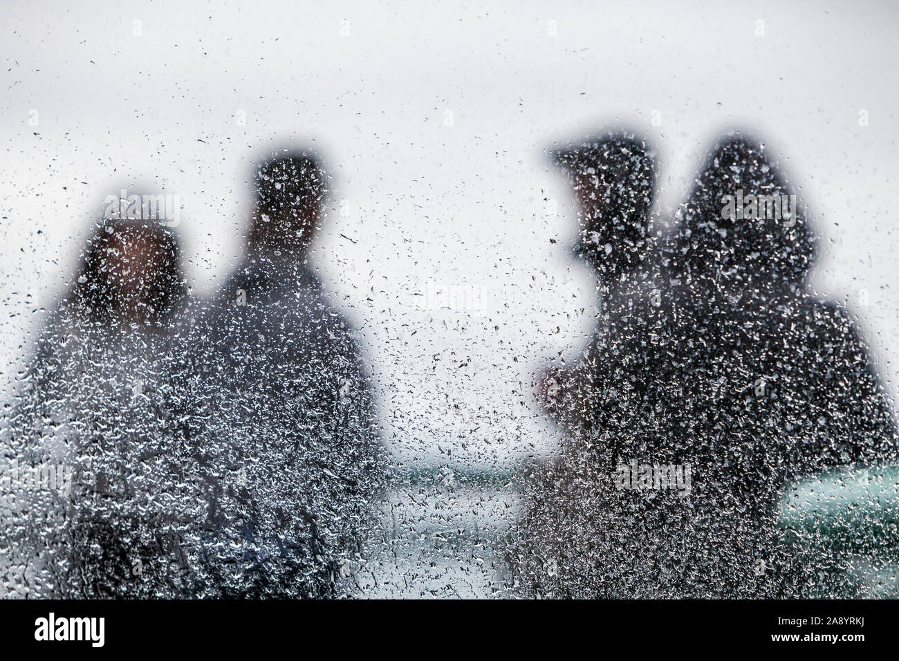 Persone in piedi sulla piattaforma esterna su un stato di Washington in traghetto la pioggia visibile attraverso una finestra coperta con gocce di pioggia, concentrarsi sulle gocce di pioggia. Foto Stock