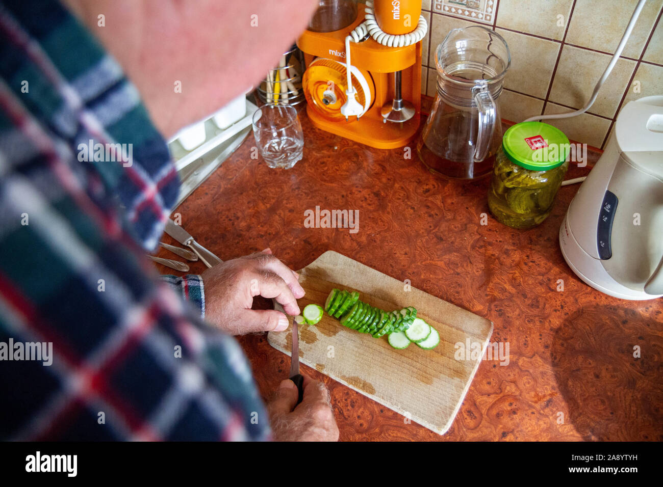 Un vecchio uomo tritare verdure su un tagliere Foto Stock