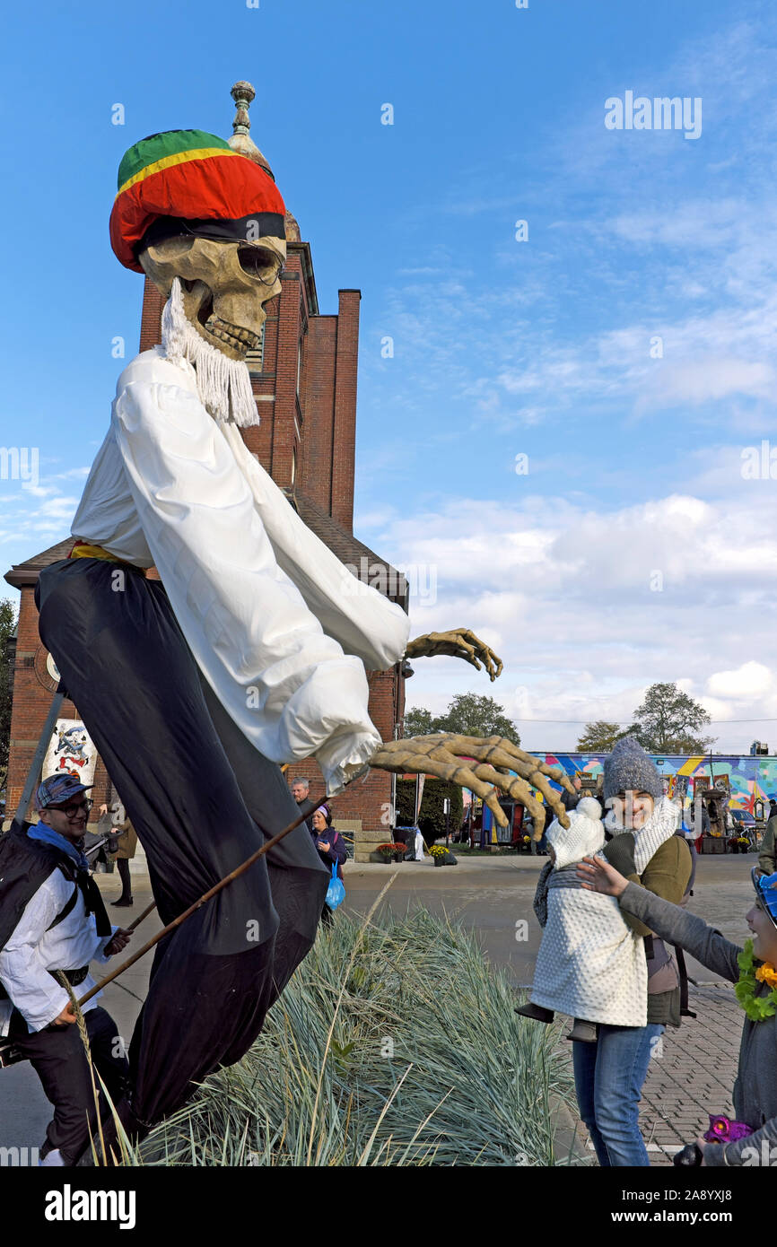 Un marionette di scheletro più grande della vita saluta un bambino durante la celebrazione del giorno dei morti nel Gordon Square District di Cleveland, Ohio. Foto Stock