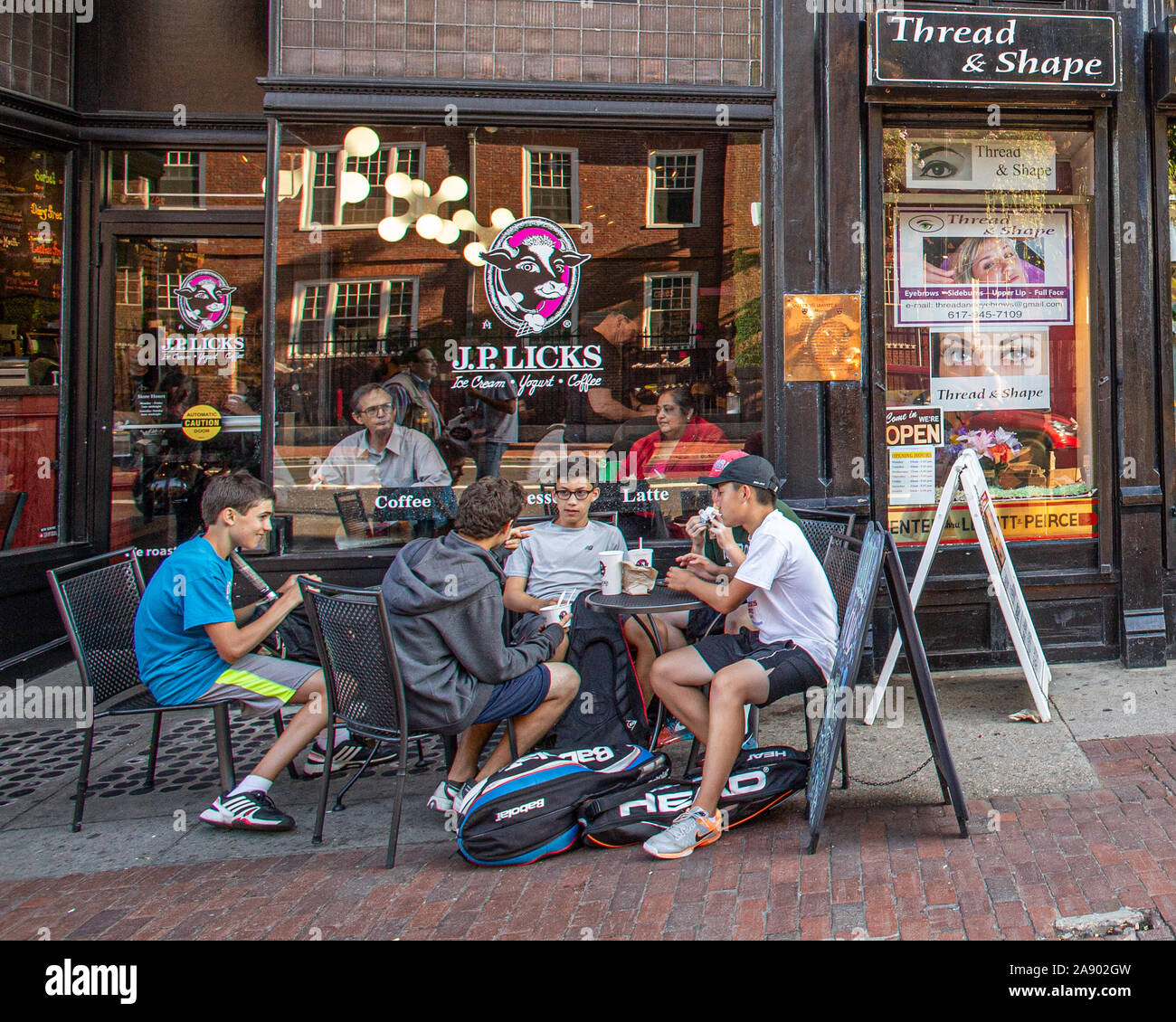 Gruppo di studenti seduti sul marciapiede davanti a JP lambisce sui Mass Ave in Cambridge Foto Stock