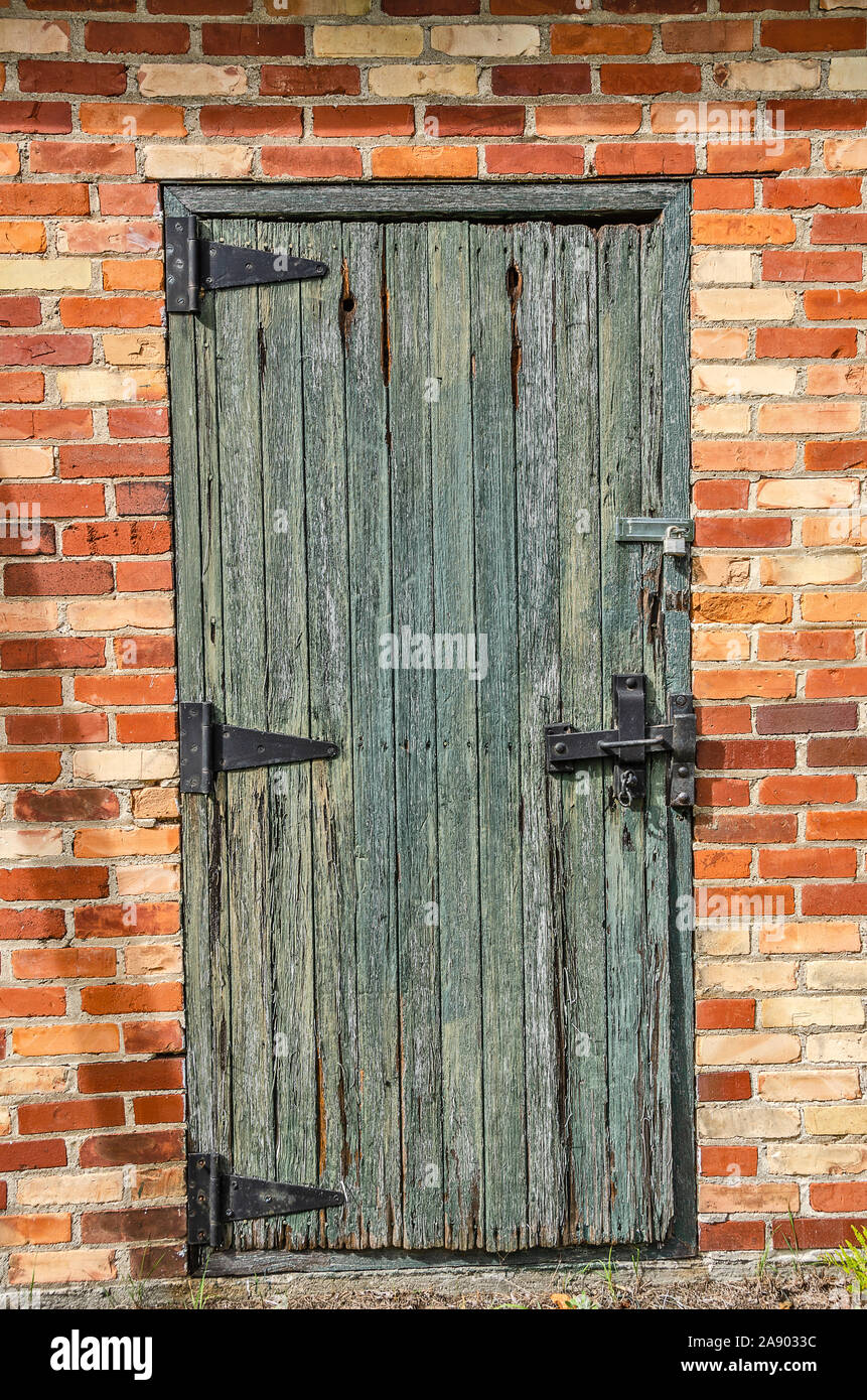 Bella e antica porta di legno con un vecchio stile cerniere su un edificio in mattoni Foto Stock