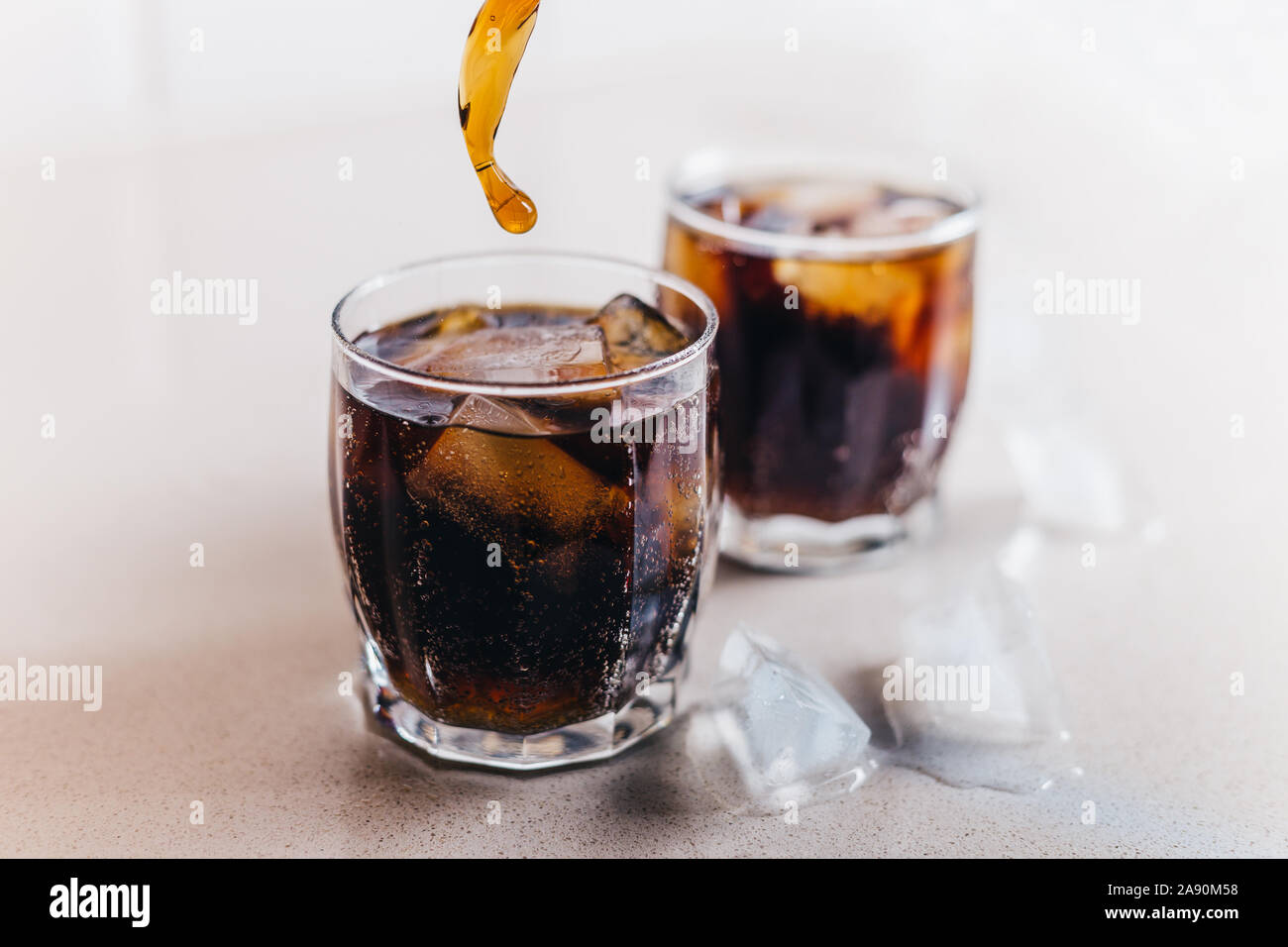 Primo piano di due bicchieri di coca cola con ghiaccio - drink dannosi Foto Stock