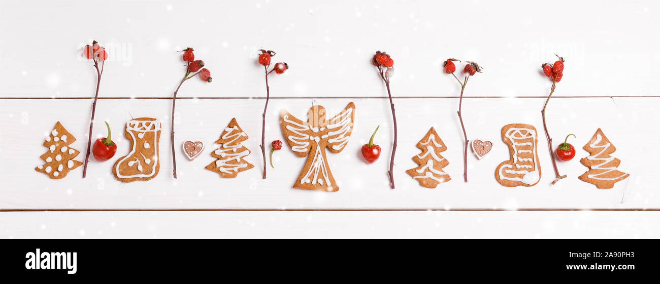 Gingerbread fegato e bacche di rosa canina, pepe, composizione di Natale, banner su un di legno bianco, scheda Sfondo. Vista superiore, piana, laici spazio copia Foto Stock