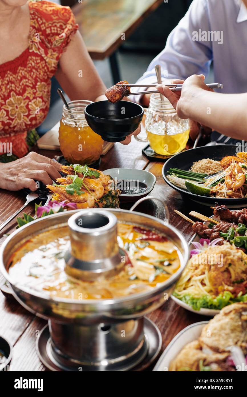 Gruppo di persone gustando piatti saporiti della cucina vietnamita durante la cena di famiglia nel ristorante Foto Stock