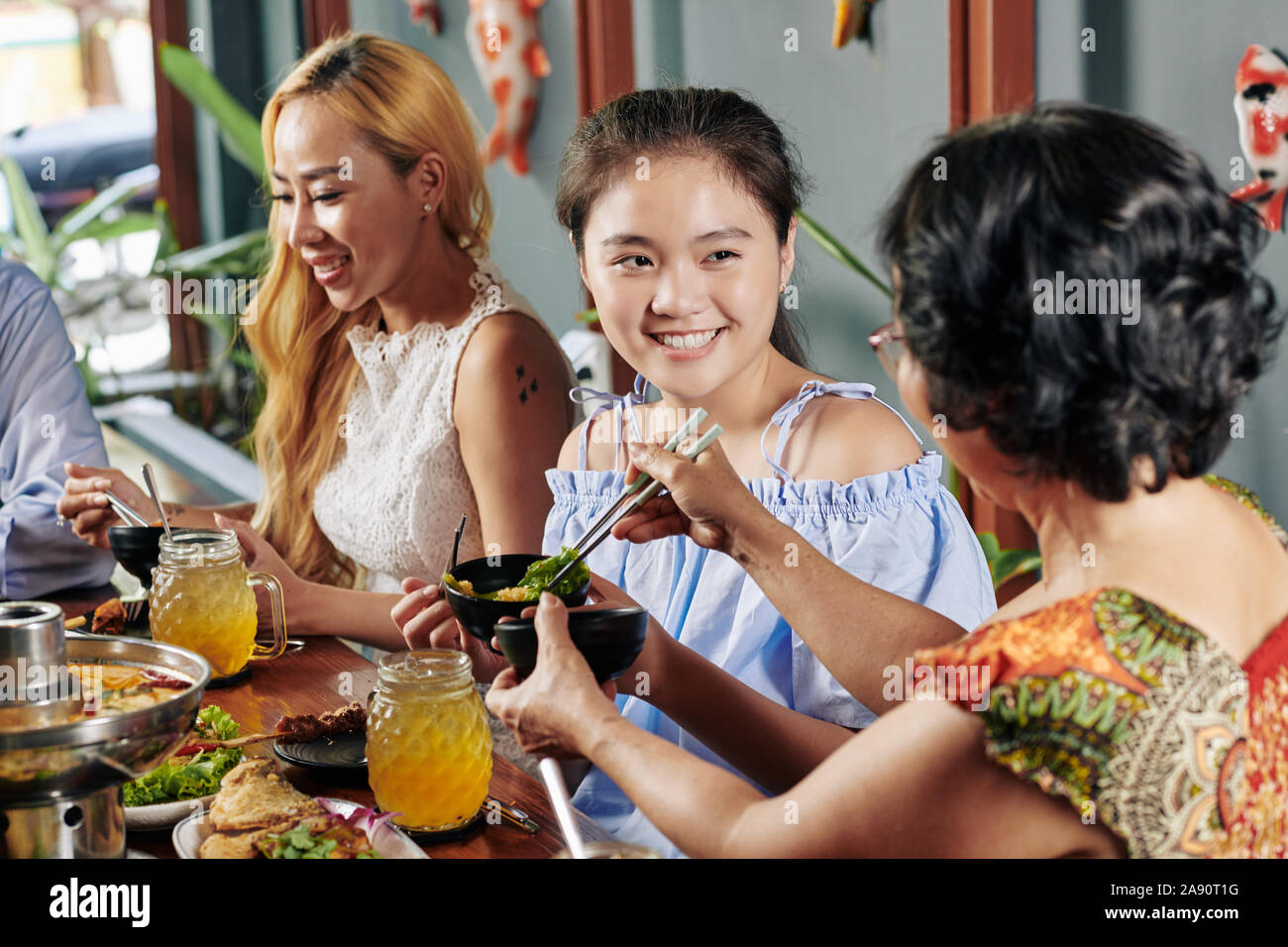 Piuttosto sorridente ragazza preteen godendo di una gustosa cena con la sua famiglia nel ristorante Foto Stock