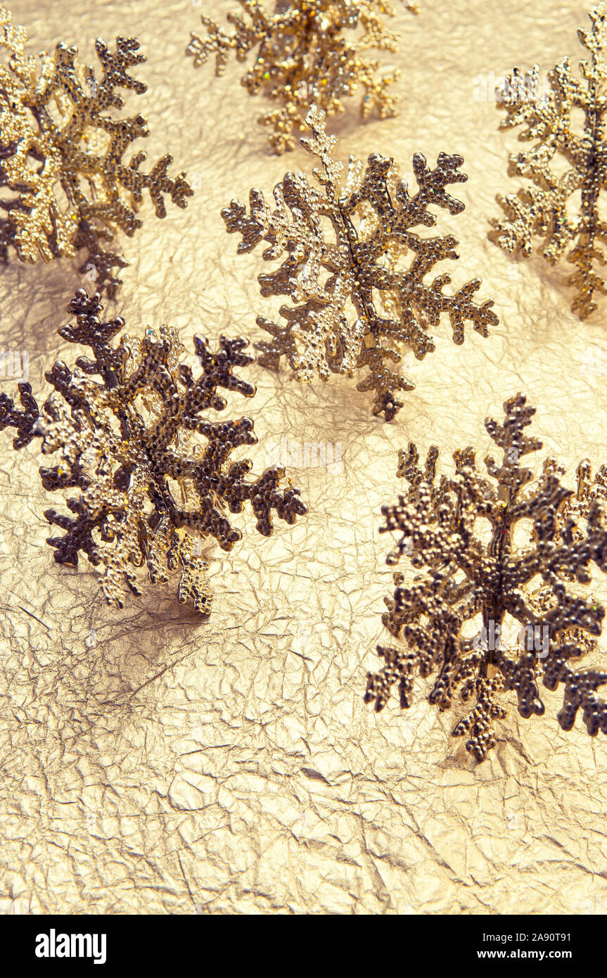 Vini spumanti oro snowflake ornamenti in appoggio sulla trama festosa crinkly fondo oro Foto Stock