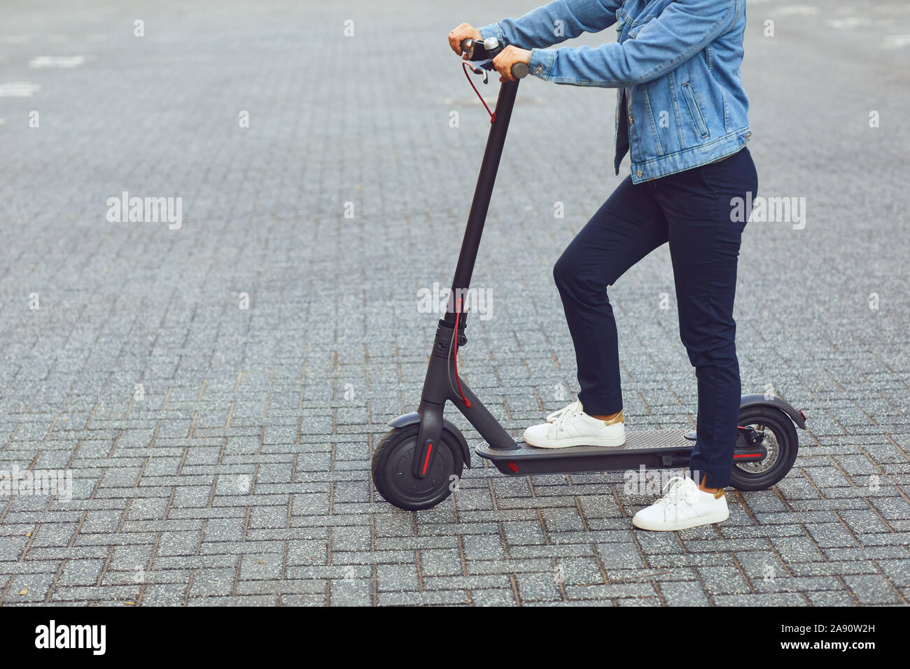 Giovane uomo in un casco cavalca un scooter elettrico su una strada di città in estate Foto Stock