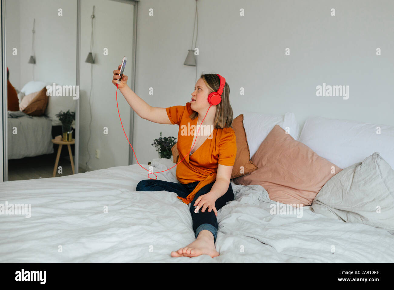 Ragazza sul letto tenendo selfie Foto Stock
