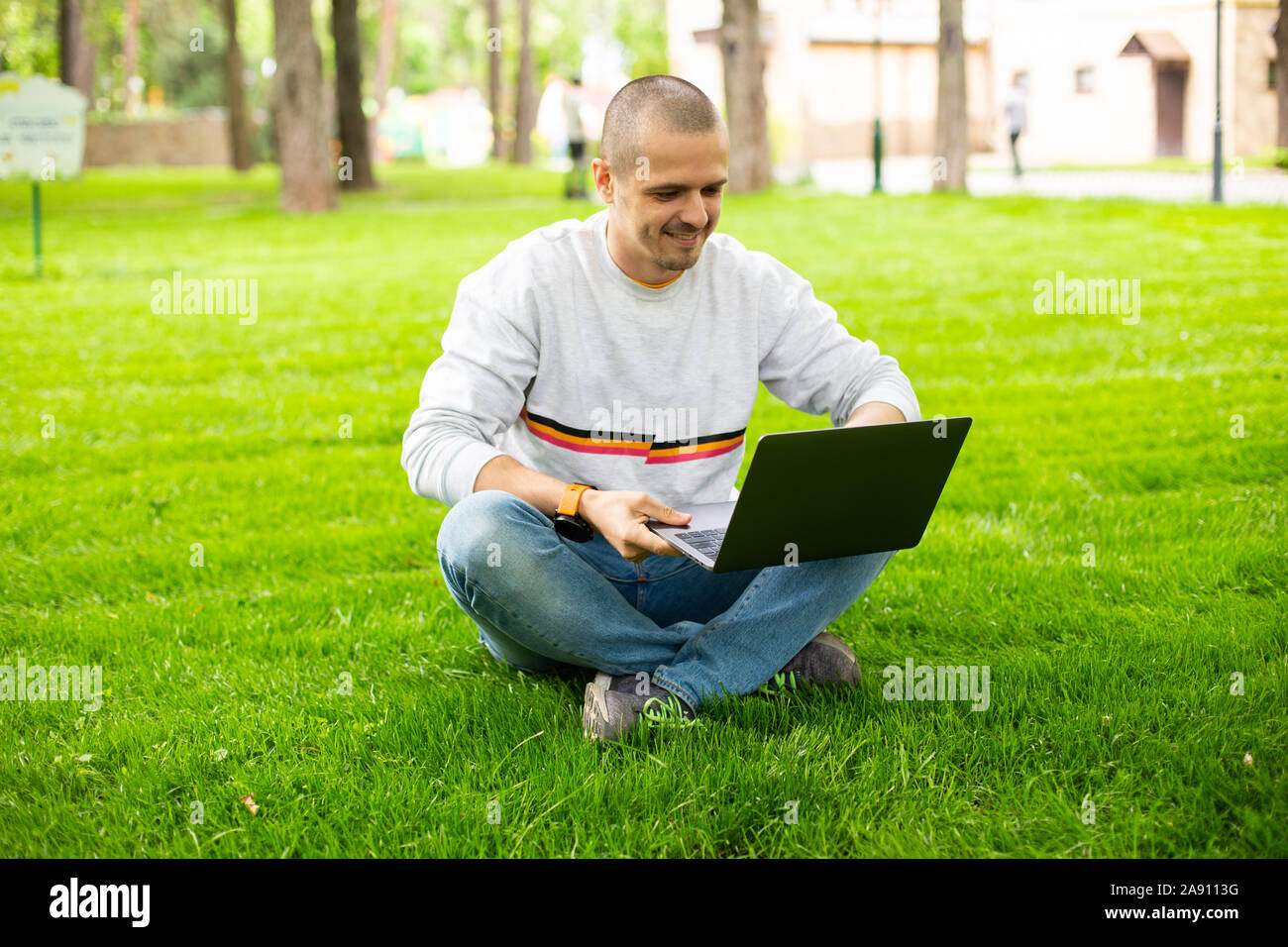 Uomo libero professionista sviluppatore che lavora su laptop seduto sul prato Foto Stock