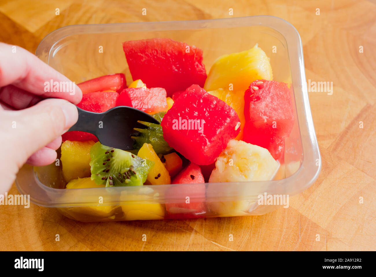 Un snack sani di una insalata di frutta tropicale in un contenitore in plastica Foto Stock