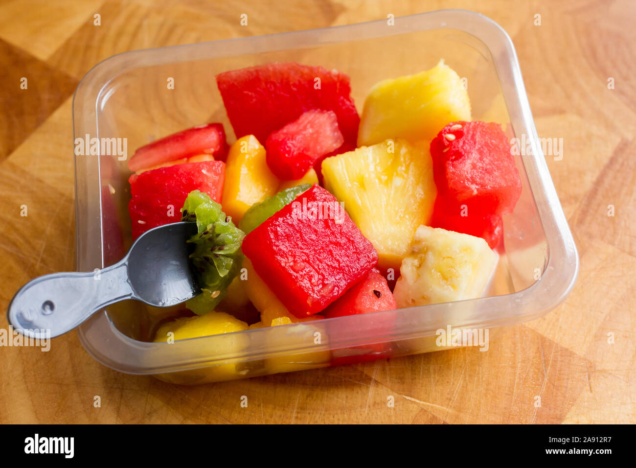 Un snack sani di una insalata di frutta tropicale in un contenitore in plastica Foto Stock