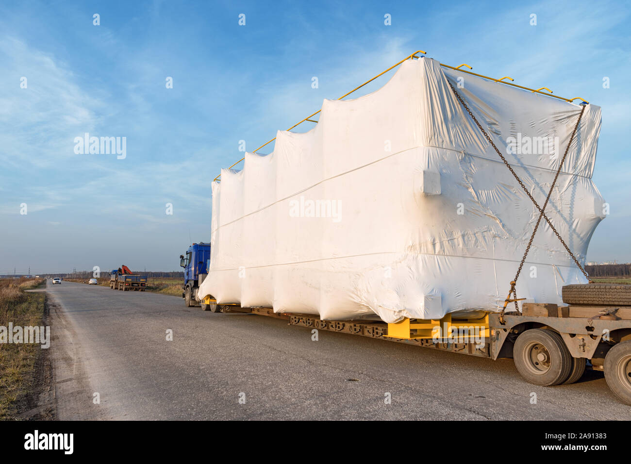 Carrello con grande fuorimisura su strada rurale. Industriali angolo ampio paesaggio Foto Stock