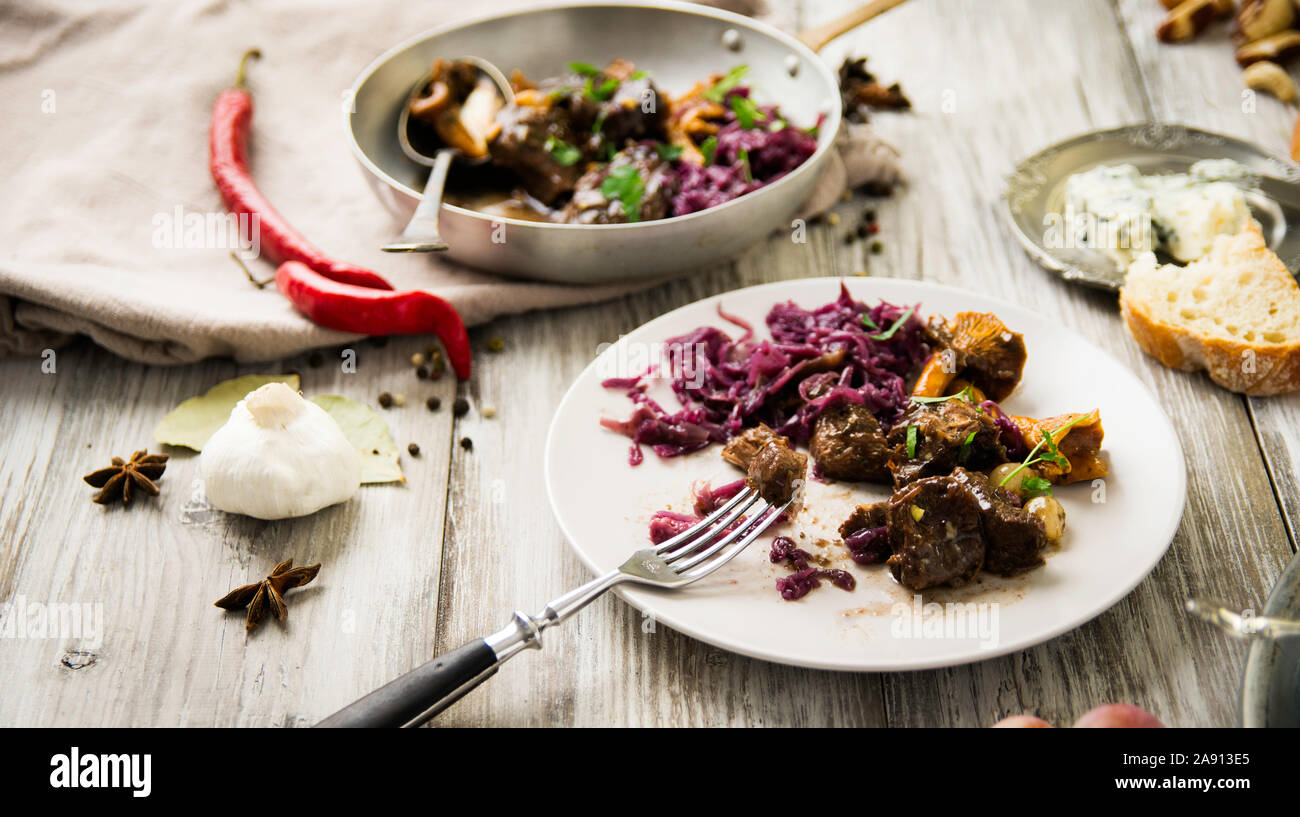 Piatto di carne di cervo sul vecchio tavolo in legno, con marmellata di frutta, formaggio e castagne, tradizionale piatto invernale con carne, bottino di caccia Foto Stock
