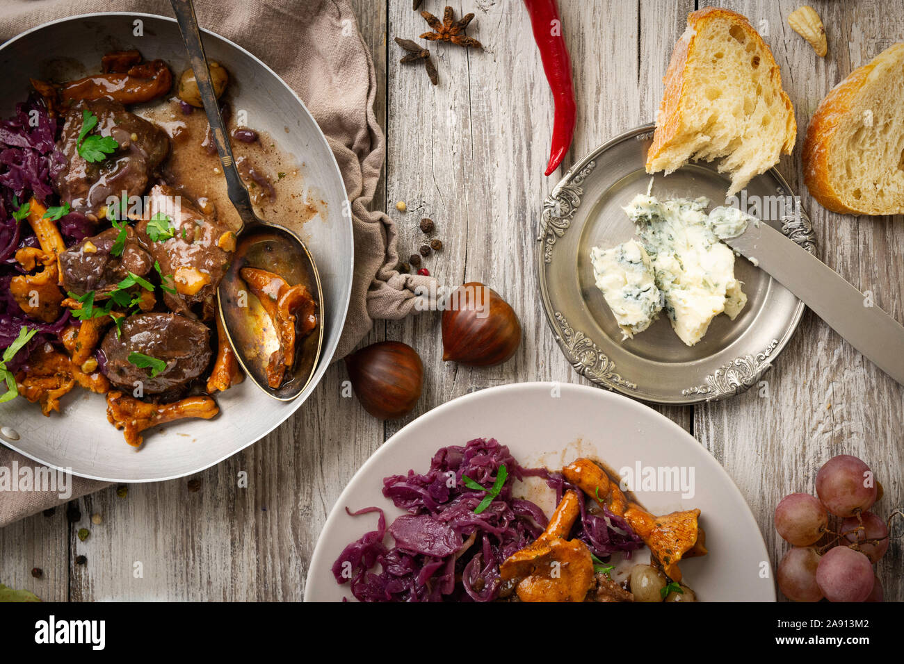 Piatto di carne di cervo sul vecchio tavolo in legno, con marmellata di frutta, formaggio e castagne, tradizionale piatto invernale con carne, bottino di caccia Foto Stock
