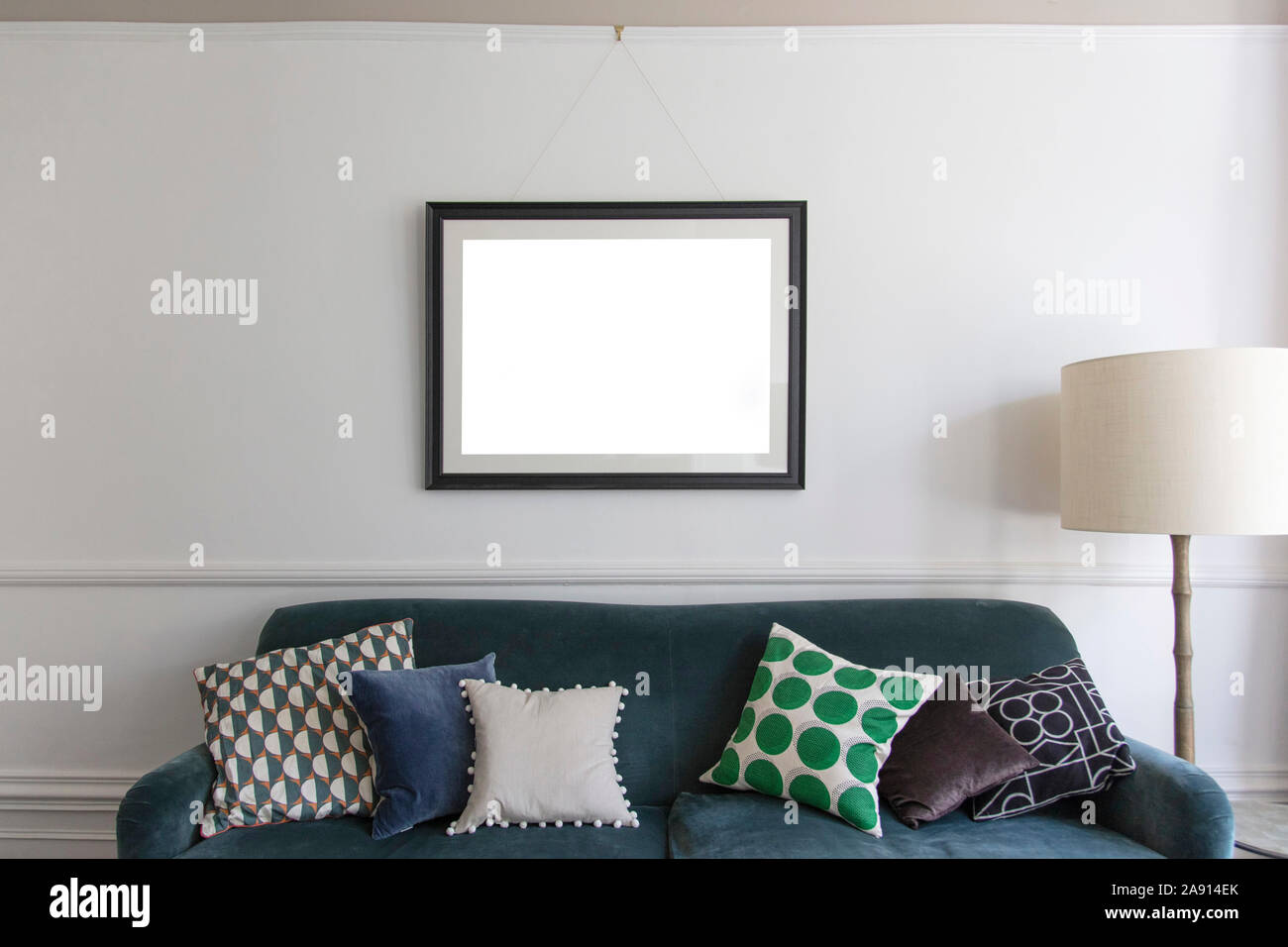 Empty picture frame appeso sopra un divano blu in una stanza vivente Foto Stock