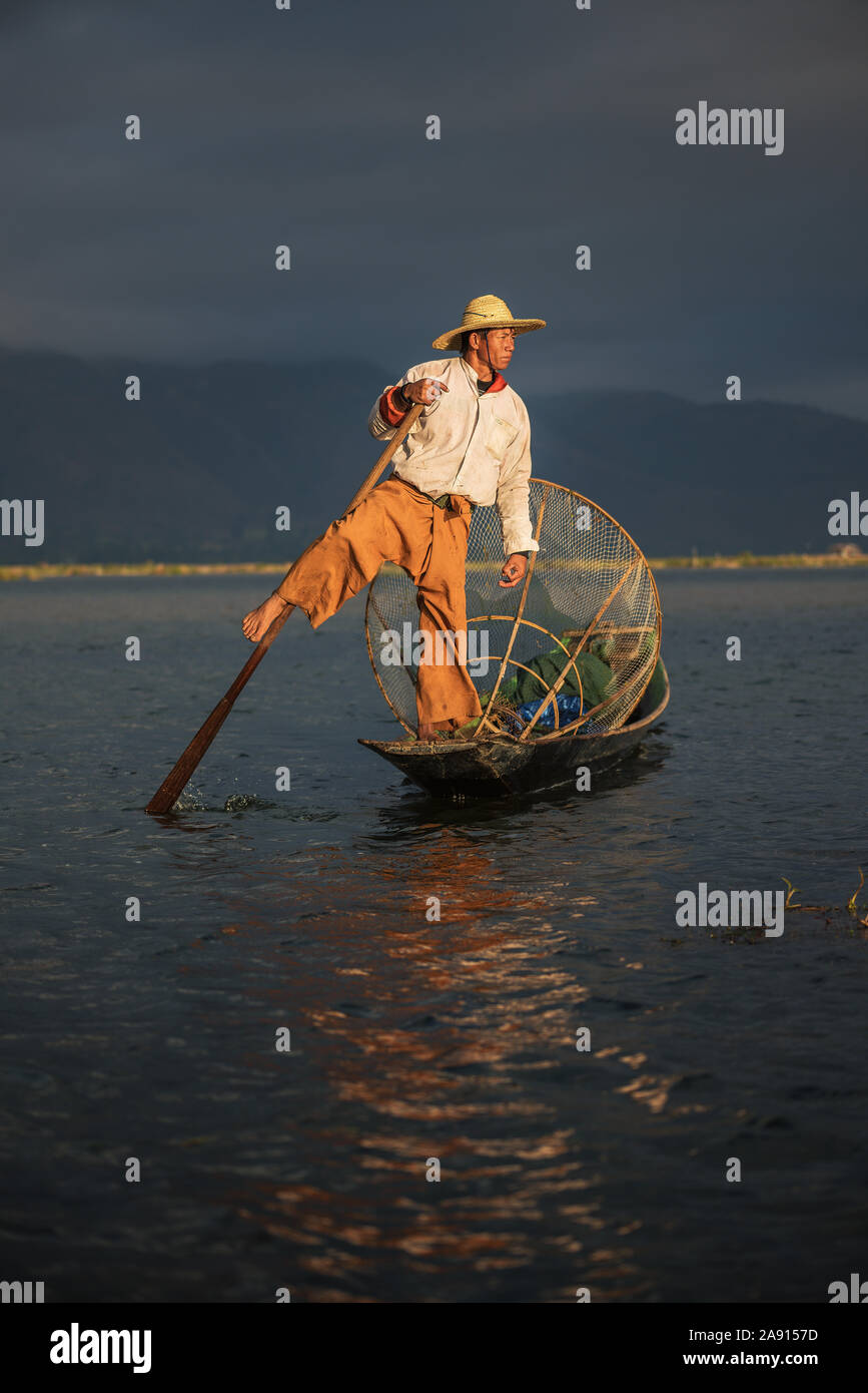 Pescatore birmano su una barca di bambù di sunrise Foto Stock