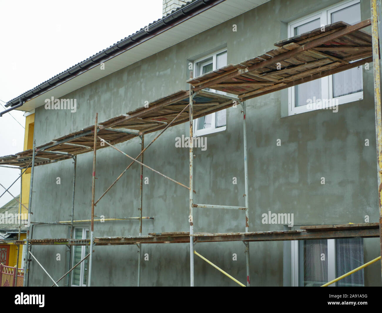 Il riscaldamento esterno di una casa privata. Lavoro all'aperto. Ci sono guide per i lavoratori. Il riscaldamento della casa. Riparazione esterna i lavori per la costruzione Foto Stock