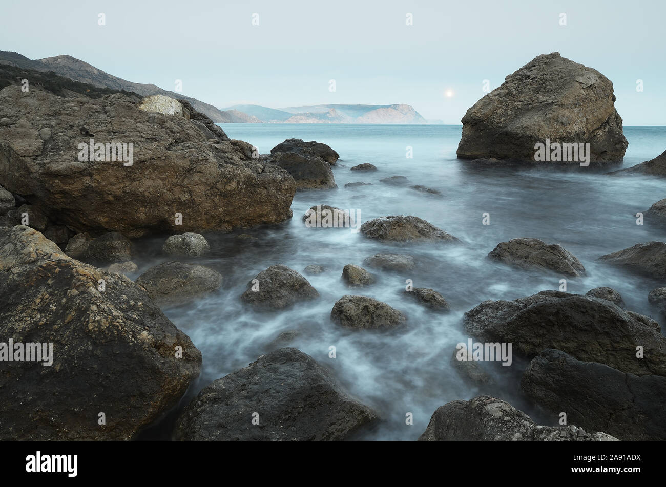 Paesaggio di mattina con il mare e le rocce sulla riva. Luna piena nel cielo Foto Stock