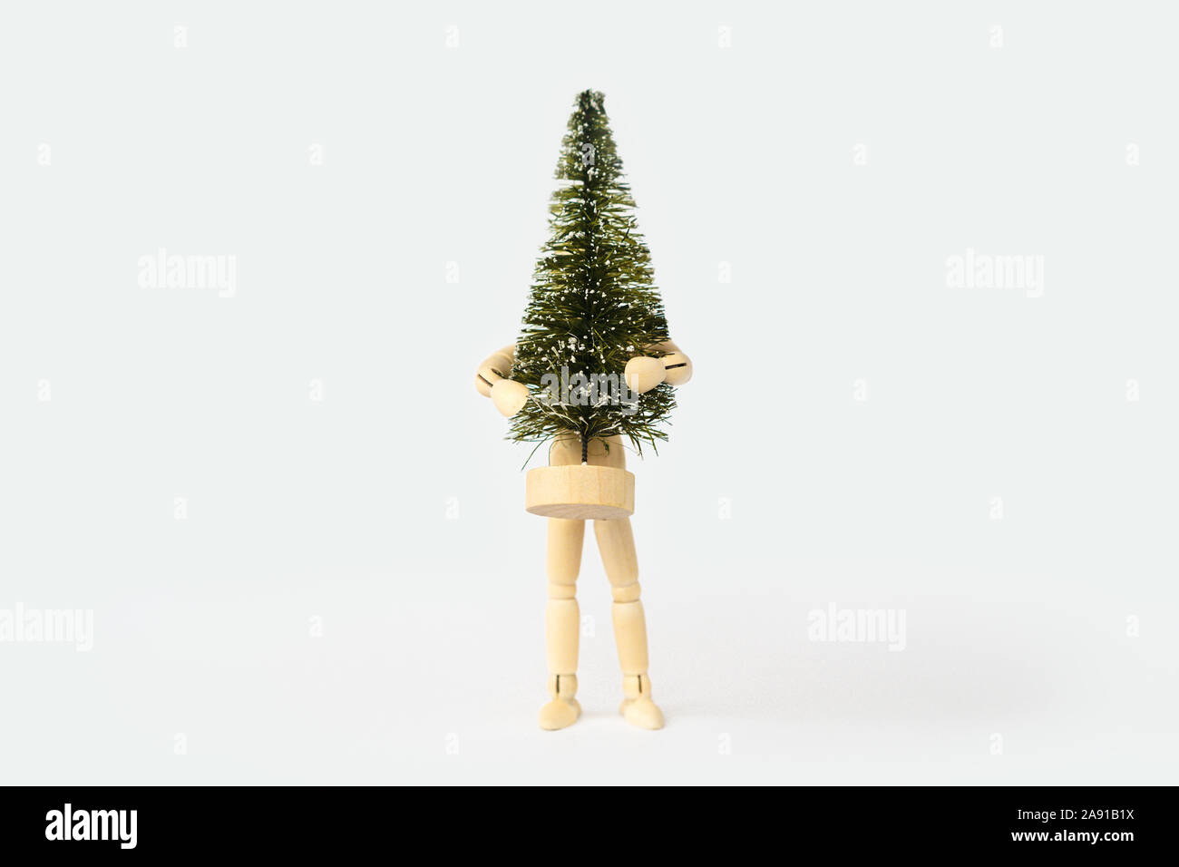 Manichino di legno uomo che tiene nelle sue mani grande albero di Natale artificiale Foto Stock