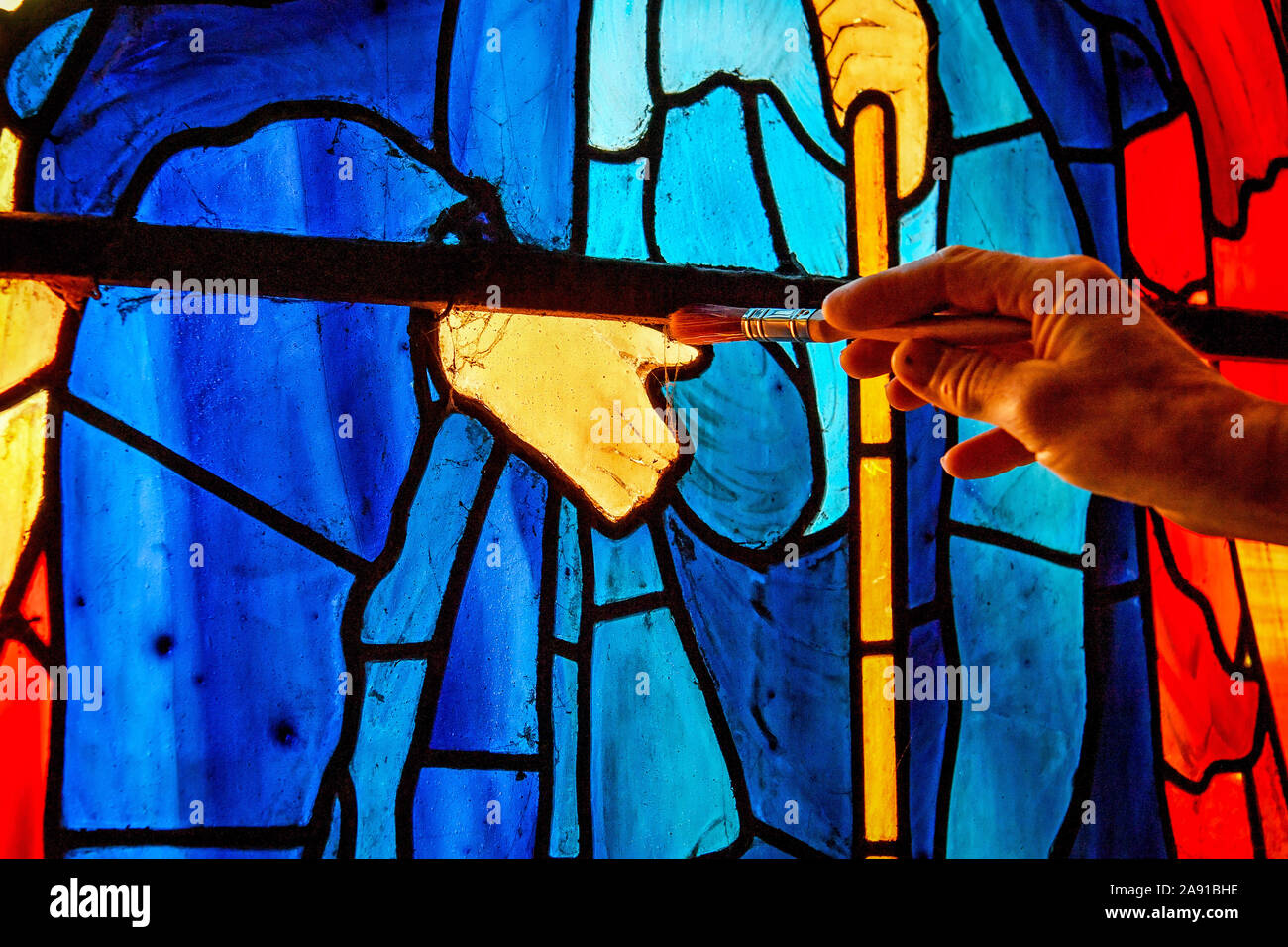 Vetro testa conservatore Sam Kelly spazzole ragnatele da un supporto di ferro sulla barra di Angeli Laudantes e Angeli Ministrantes vetrate a Cattedrale di Salisbury come lavori di restauro per pulire, conservare e ripristinare le finestre, installato nel 1879, ottiene in corso. Foto Stock