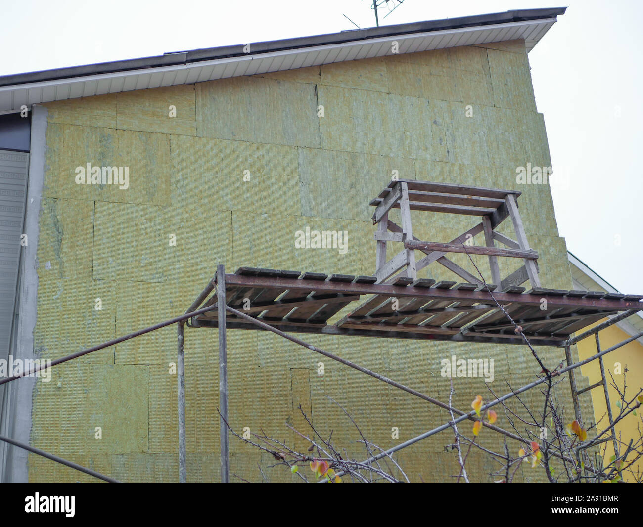 Il riscaldamento esterno di una casa privata. Lavoro all'aperto. Ci sono guide per i lavoratori. Il riscaldamento della casa. Riparazione esterna i lavori per la costruzione Foto Stock