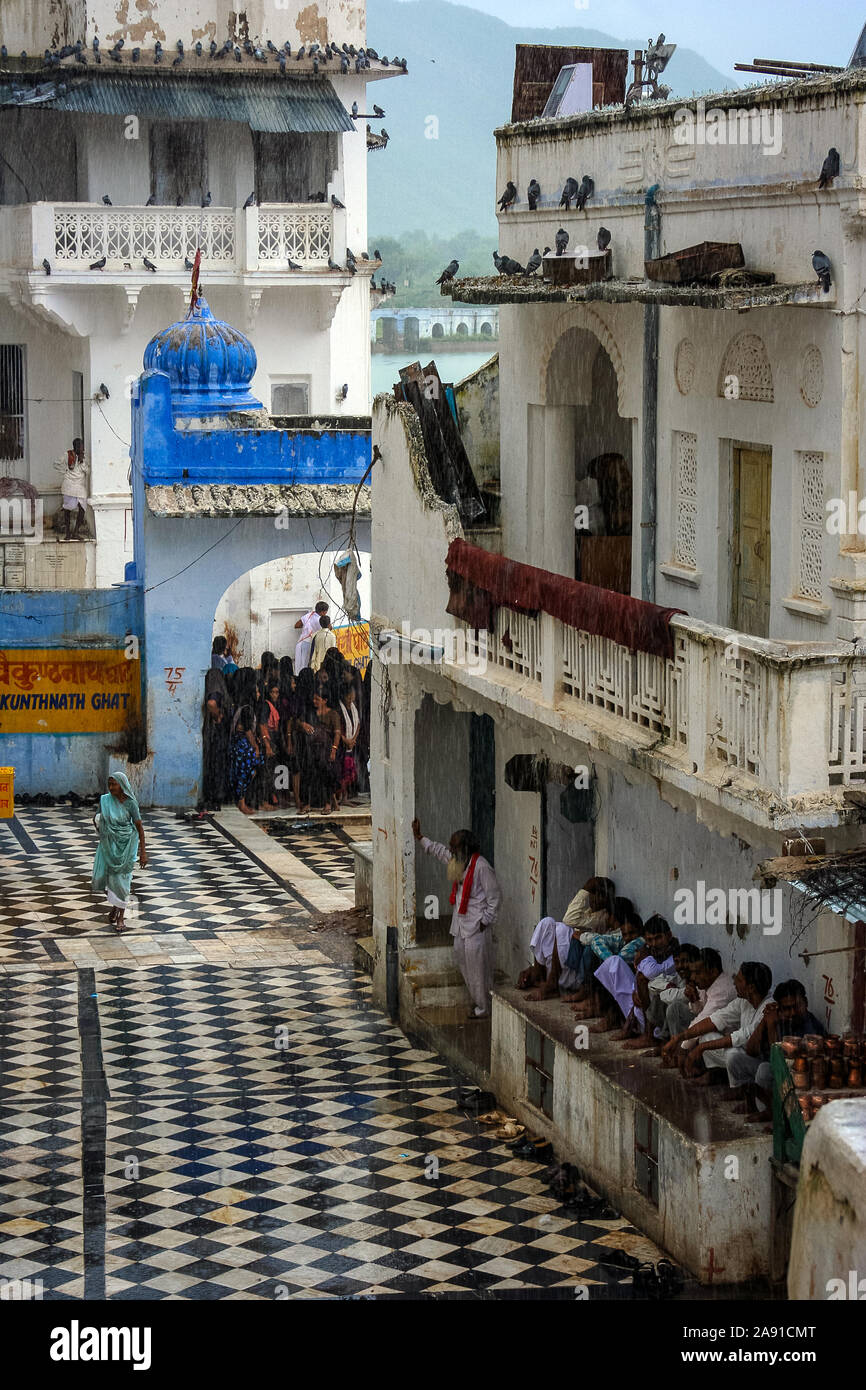 Pushkar, Rajasthan, India: alcune persone riparo dalla pioggia sotto i tetti degli edifici Foto Stock