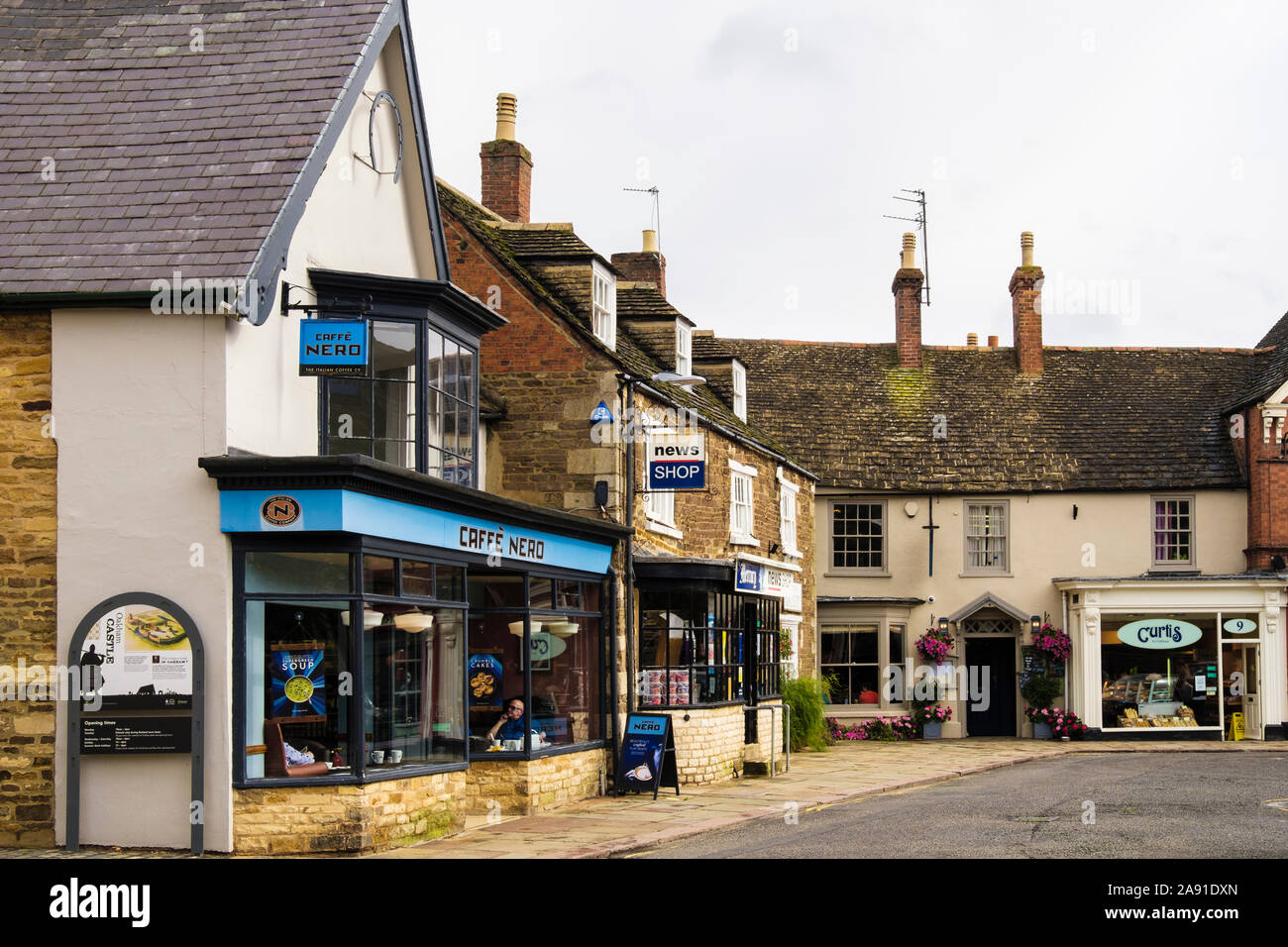 Cafe Nero e nei piccoli negozi di pittoreschi edifici antichi. Market Place, Oakham, Rutland, Inghilterra, Regno Unito, Gran Bretagna Foto Stock