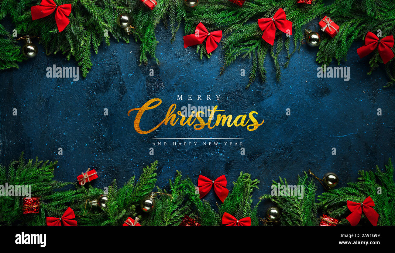 Buon Natale biglietto di auguri su sfondo nero incorniciata da rami di abete e decorazione Foto Stock