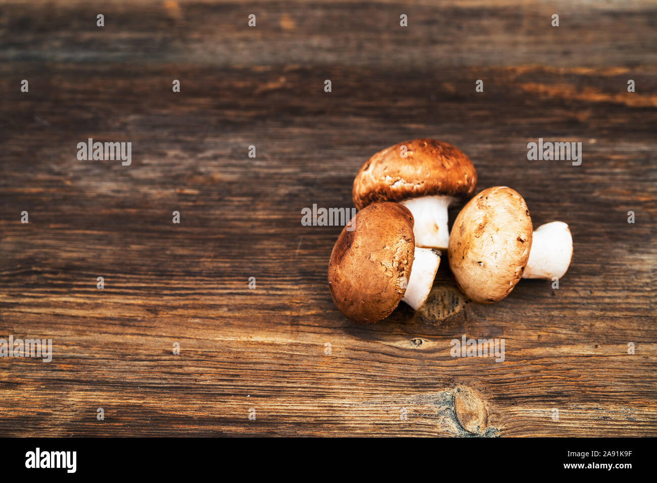 Pila di deliziosi funghi champignon su sfondo di legno. Foto Stock