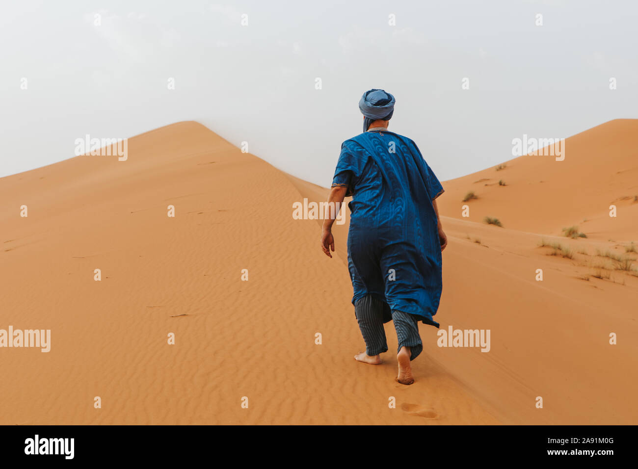L'uomo con il classico riff vestiti a piedi dalle dune del deserto da soli. Foto Stock