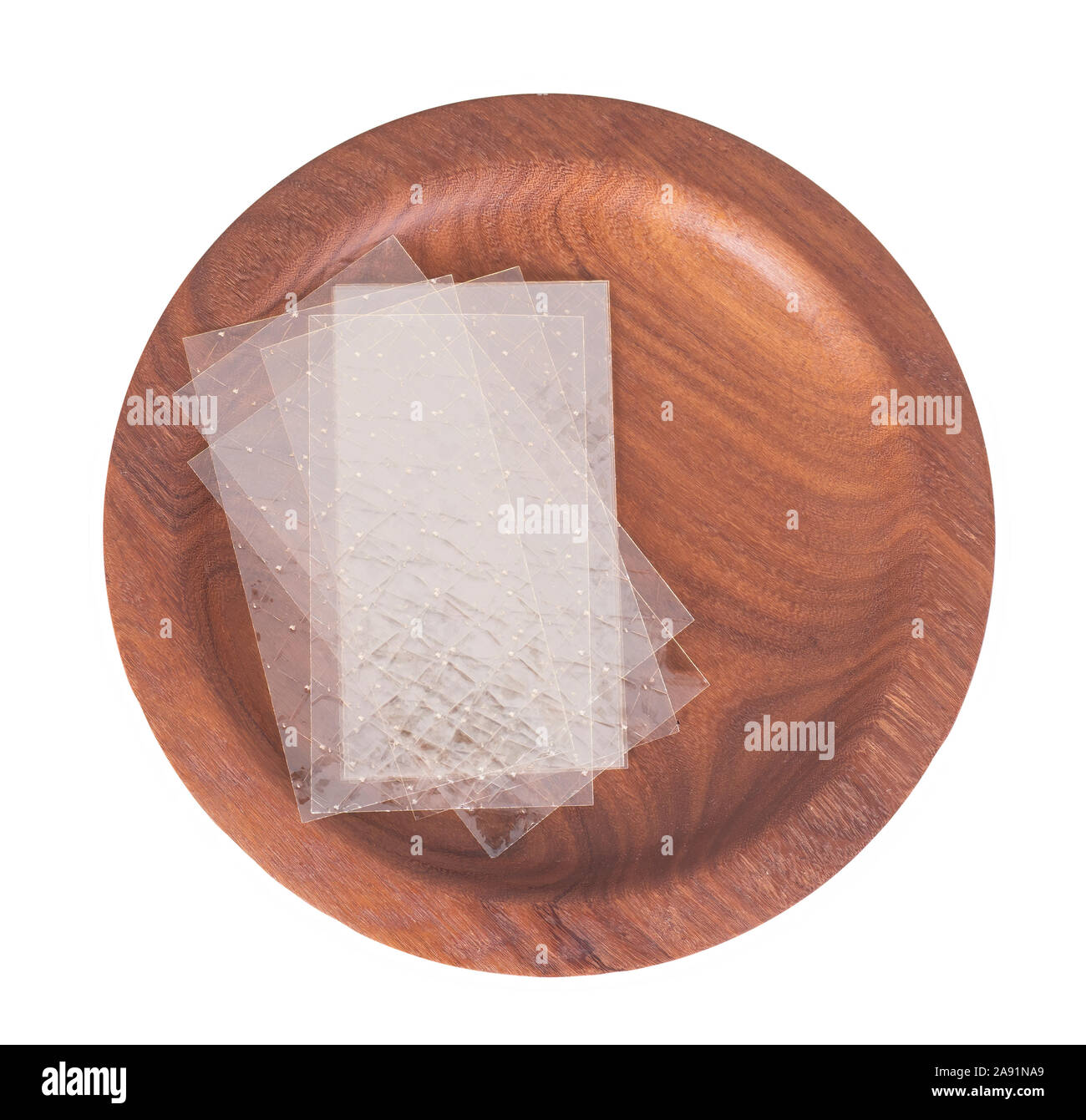 Fogli di gelatina incolore aka gelatina in foglie su un piatto di legno isolato su bianco. Ingrediente alimentare. Foto Stock