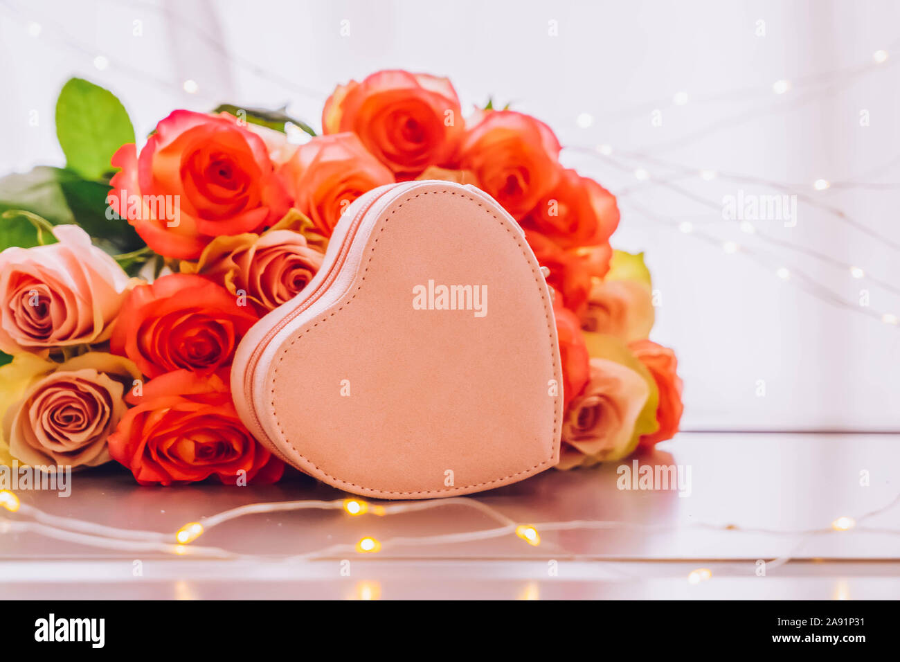 Rose fiori freschi bouquet sulla tabella grigia dalla finestra con cuore rosa confezione regalo, tonica Foto Stock