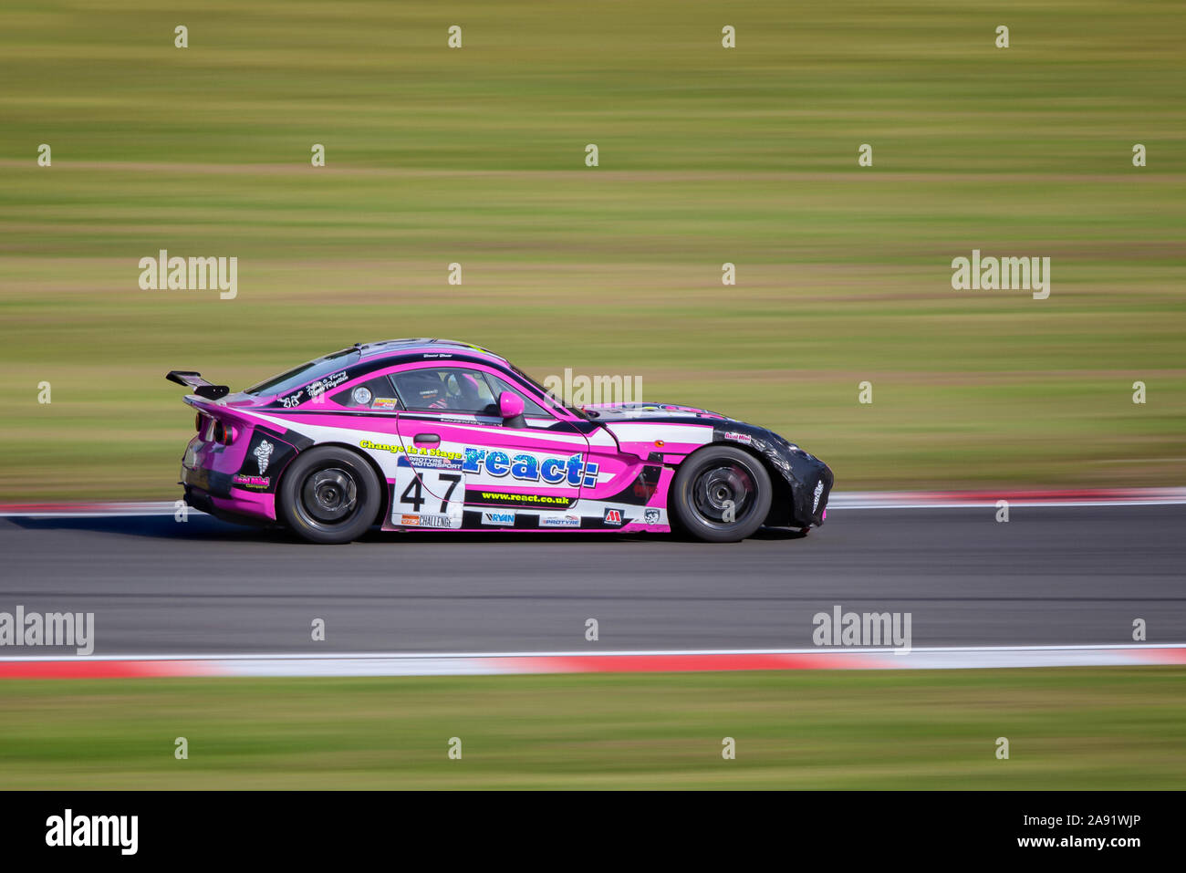 Macchina da corsa sul lato pista panoramica a Donington Park rosa Ginetta G40 race car Foto Stock