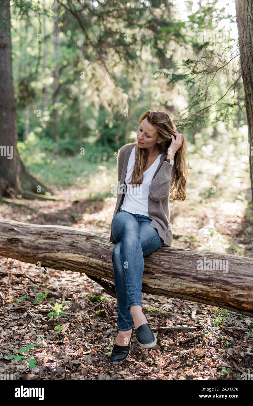Donna seduta sul log in foresta Foto Stock
