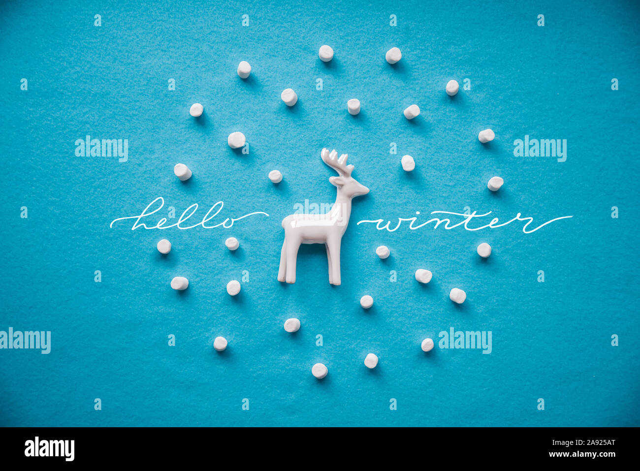 Ciao concetto d'inverno. Composizione creativa renne , marshmallow decorativo neve su sfondo blu Foto Stock